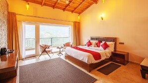 A hotel room with a large bed, a desk, a chair, a small table, and a balcony with a view. - Captains Paradise (Dhari)
