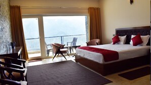 A hotel room with a large bed, a desk, a chair, and a balcony with a view. - Captains Paradise (Dhari)