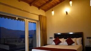 A bedroom with a large bed, a view of the mountains through a sliding door, and a balcony. - Captains Paradise (Dhari)