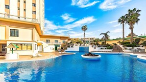 A hotel pool area with a large pool, lounge chairs, and palm trees. - Panoramic apartment in club Paraiso ocean view (Adeje)