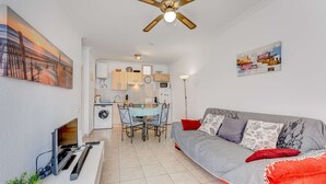 Ein kompakter Wohnraum mit Sofa, Esstisch, Waschmaschine und Fernseher.