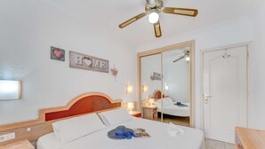 Ein Hotelzimmer mit einem Bett, Nachttischen, einem Deckenventilator, einem Spiegel und einer Tür.
