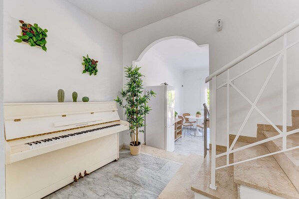 A modern interior with a piano, a staircase, and a dining area. - Oasis Golf Spacious Family Duplex (Arona)