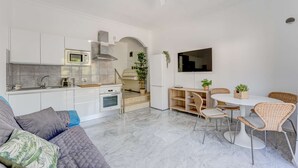 A modern kitchen with white cabinets, a microwave, and a stove. There is a dining area with wicker chairs and a table.