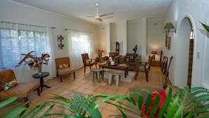 Un amplio salón con ventilador de techo, un sofá, una mesa de centro y varios objetos decorativos.