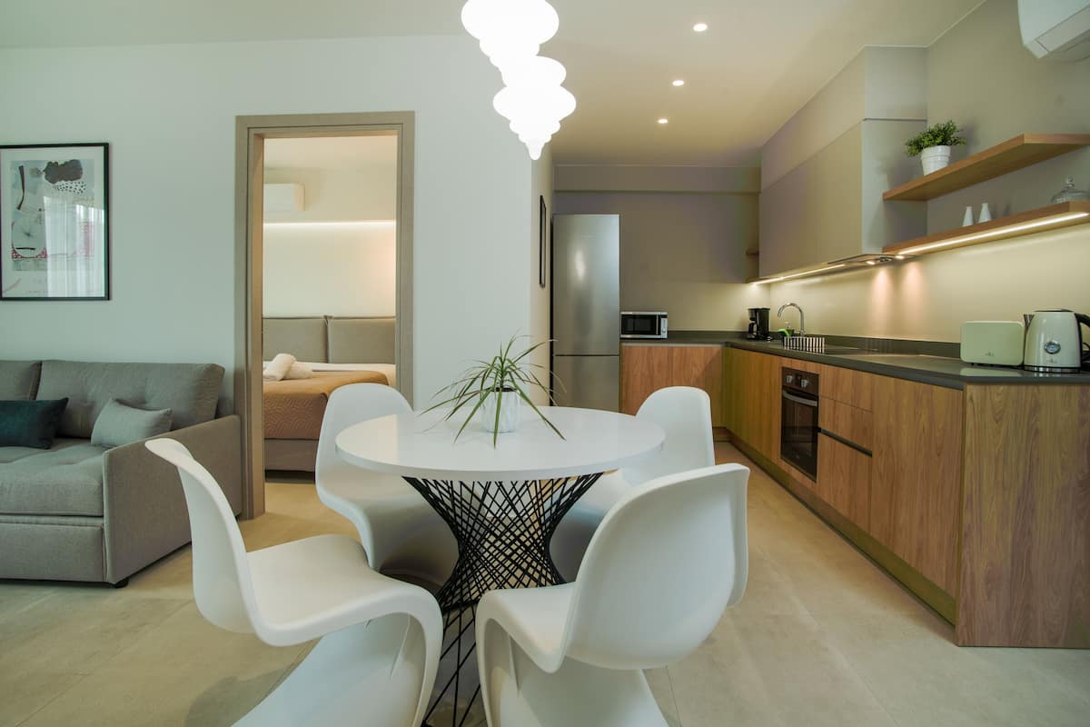 A modern kitchen with a round dining table, white chairs, and a built-in oven.