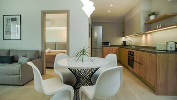 A modern kitchen with a round dining table, white chairs, and a built-in oven.