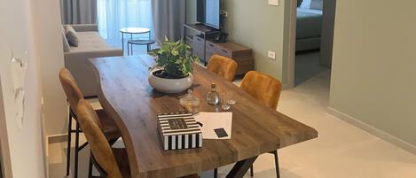 A modern dining area with a wooden table, chairs, and a potted plant.