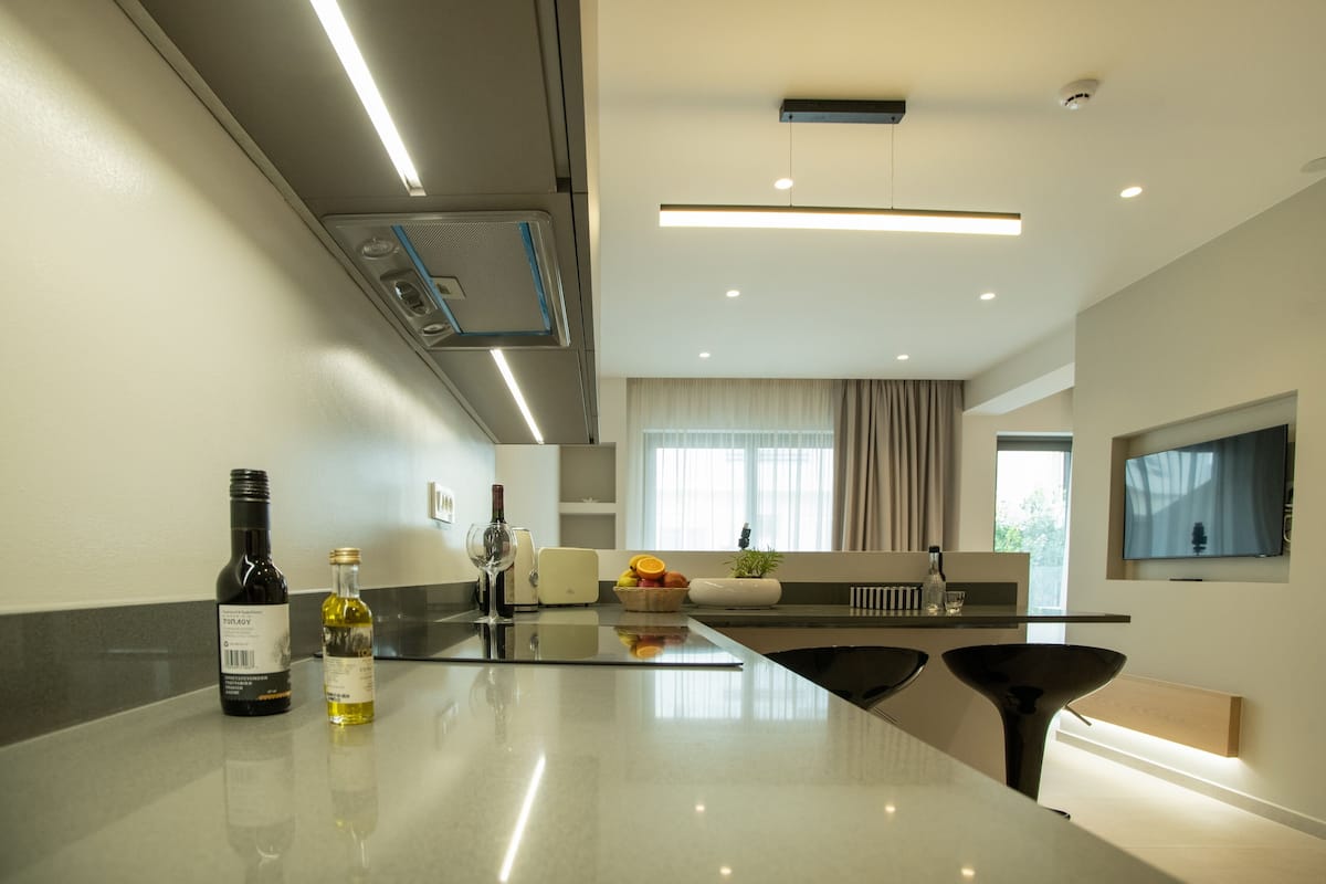A modern kitchen with a central island, built-in appliances, and a large window with curtains.