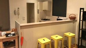 Eine kompakte Küche mit Gasherd, einem kleinen Fenster und einer Theke mit Hockern.