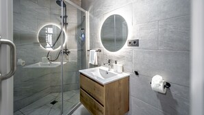 Ein modernes Badezimmer mit einer gläsernen Duschkabine, einem Holzwaschtisch und zwei Wandspiegeln.
