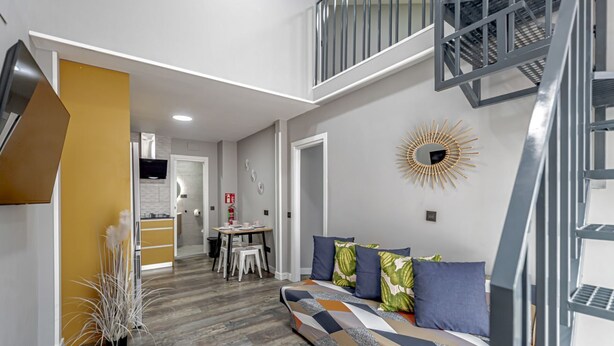 Ein modernes Interieur mit einer Couch, einem Essbereich und einer Treppe.