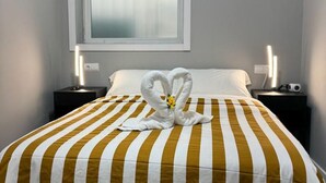 Une chambre d’hôtel avec un lit recouvert d’une couvre-lit à rayures, une fenêtre à vitres dépolies et des lampes de chevet.