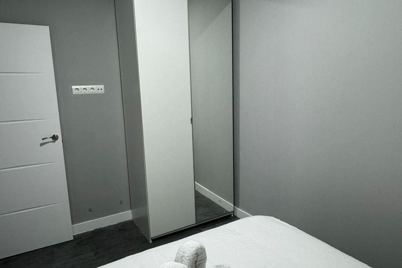 A room with a bed, a wardrobe, and a mirror.