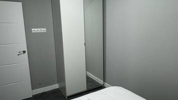 A room with a bed, a wardrobe, and a mirror.