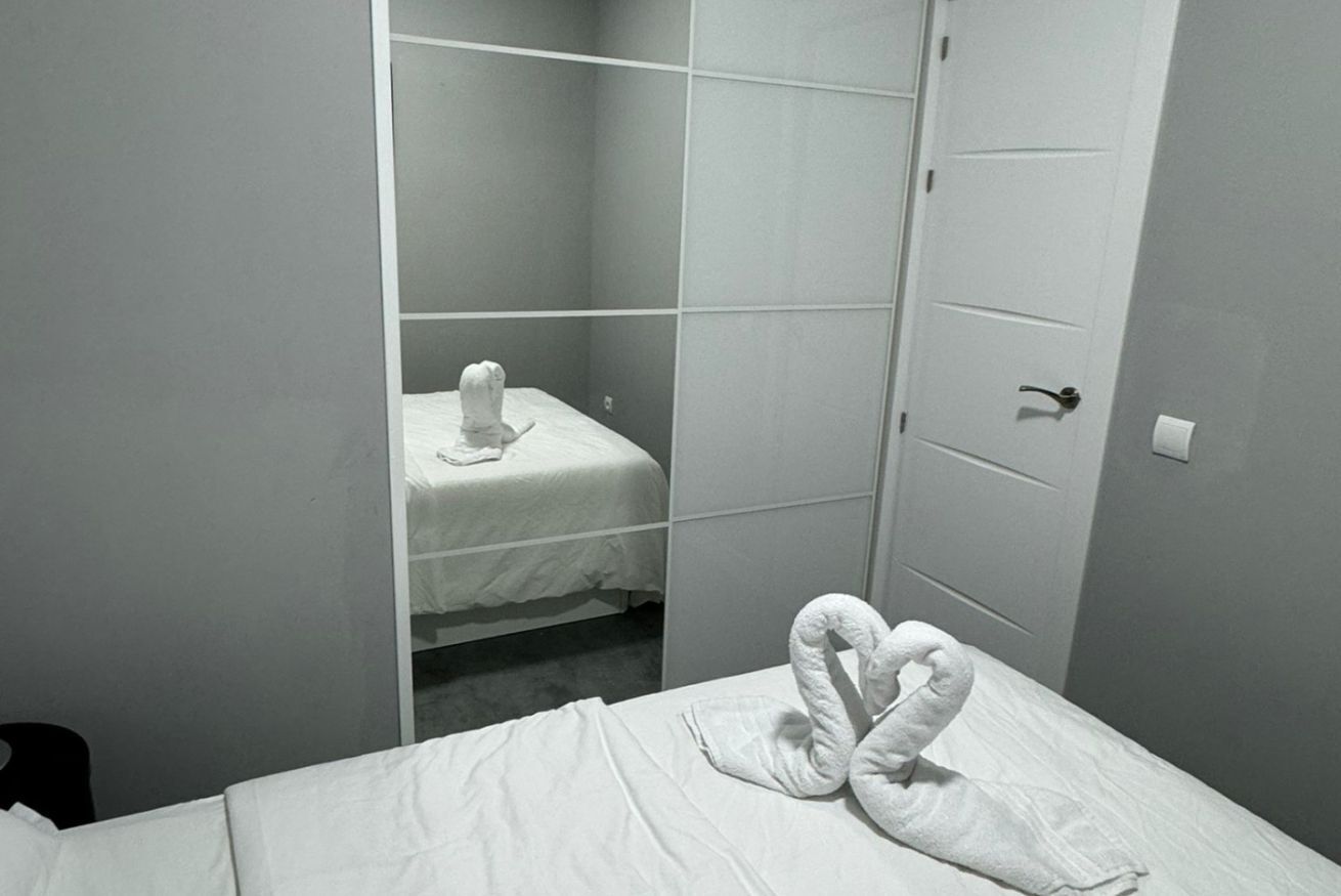 Een hotelkamer met een bed, een handdoeksculptuur en een deur.