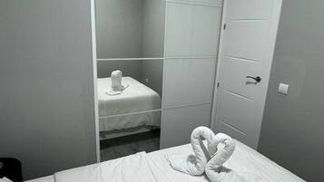 Een hotelkamer met een bed, een handdoeksculptuur en een deur.