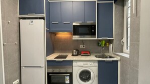 Une cuisine compacte équipée d’un réfrigérateur, d’un four à micro-ondes, d’un four et d’un lave-linge.