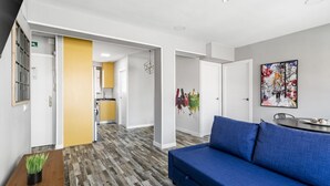 A modern hotel lobby with a blue sofa, a wooden table with a plant, and a colorful abstract painting on the wall. - Modern near Santiago Bernabéu - AZCA Apartment (Madrid)