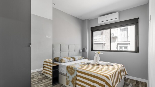A bedroom with a bed, a window, and a wall-mounted air conditioner. - Modern near Santiago Bernabéu - AZCA Apartment (Madrid)