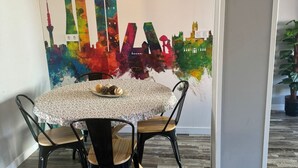 A dining area with a round table, two chairs, and a colorful cityscape mural on the wall. - Modern near Santiago Bernabéu - AZCA Apartment (Madrid)
