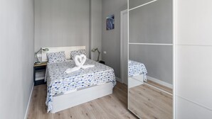 Une chambre à coucher comprenant un lit, des tables de chevet, un miroir et une armoire.