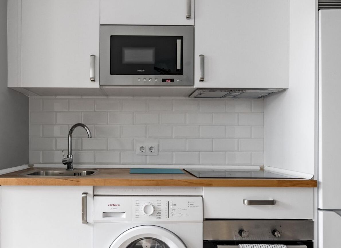 Una cucina con microonde, lavatrice e forno.