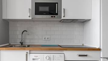 Una cucina con microonde, lavatrice e forno.