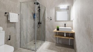 Une salle de bain moderne avec une douche à parois de verre, des toilettes, un lavabo avec un miroir et un porte-serviettes.