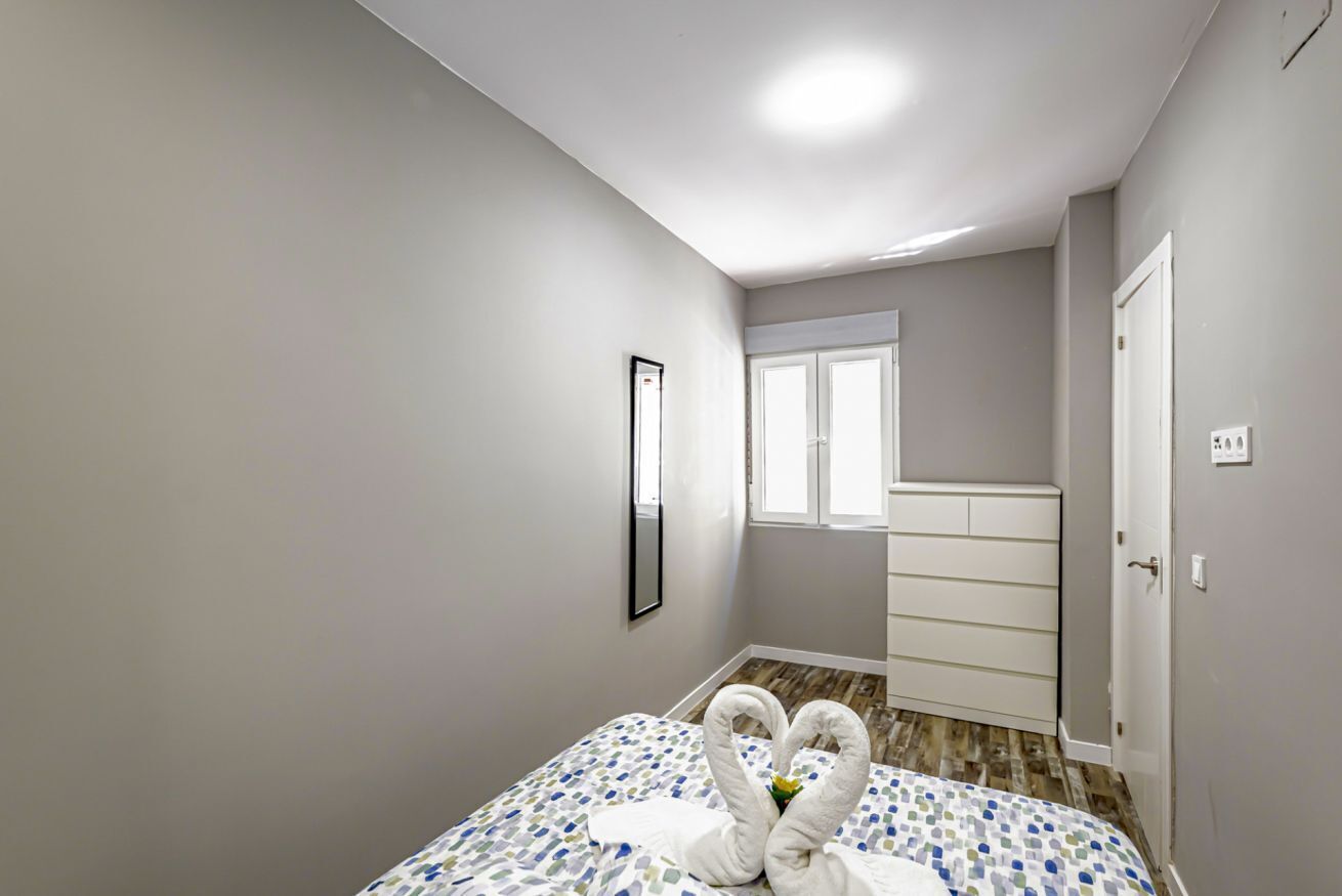 Un dormitorio con cama, cómoda, espejo y ventana.