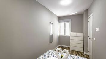 Un dormitorio con cama, cómoda, espejo y ventana.