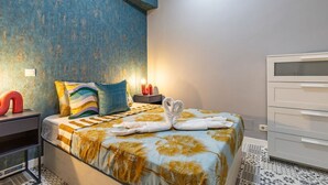 Ein Schlafzimmer mit Bett, Kissen, einem Nachttisch, einer Kommode und einer Wand-Klimaanlage.