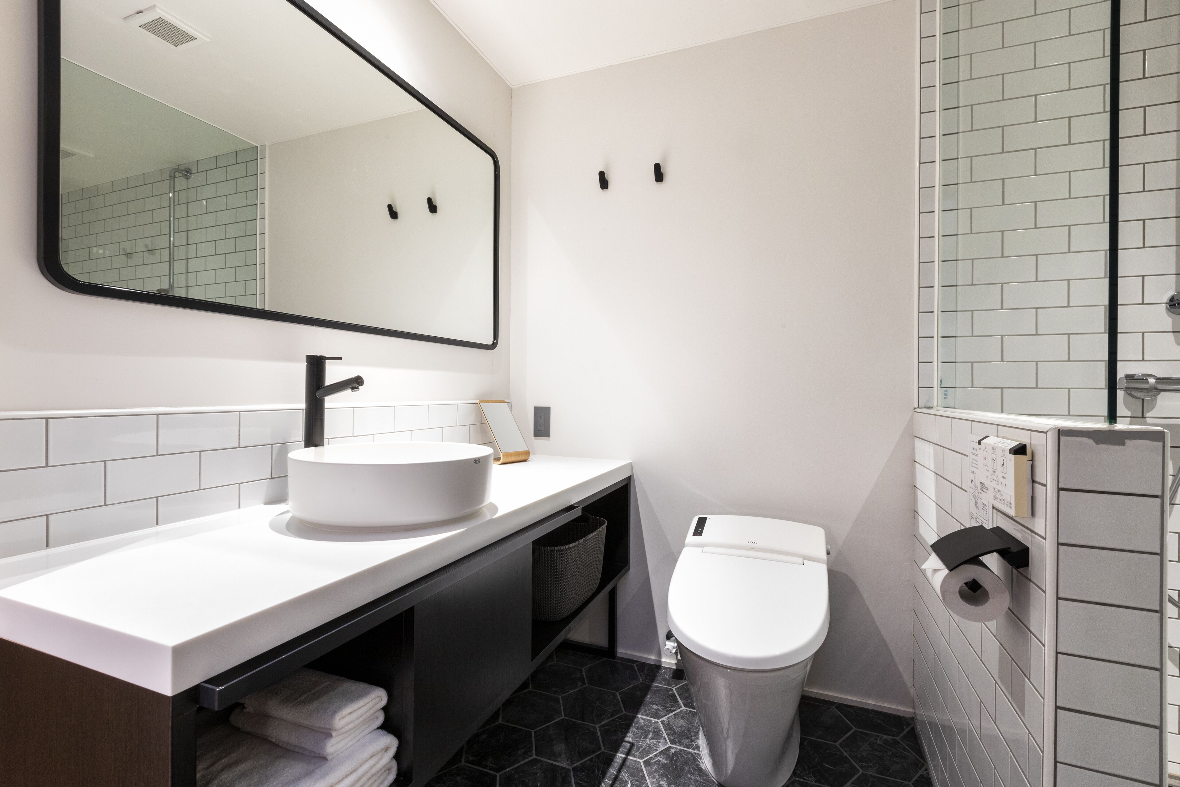 A modern bathroom with a white sink, black faucet, and a toilet.