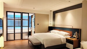 A modern hotel room with a large bed, a bedside table, a nightstand, and a view through a sliding glass door. - Mehood Elegant Hotel (Guangzhou Baiyun Airport T2 Terminal) (Guangzhou)