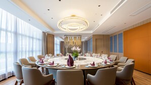 A conference room with a round table, chairs, and a chandelier. - Mehood Elegant Hotel (Guangzhou Baiyun Airport T2 Terminal) (Guangzhou)