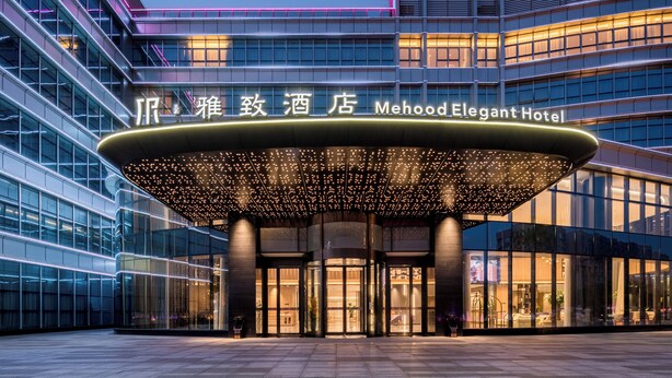 The exterior of the Mehood Elegant Hotel with a modern glass facade and a distinctive illuminated entrance canopy. - Mehood Elegant Hotel (Guangzhou Baiyun Airport T2 Terminal) (Guangzhou)