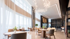 A spacious hotel lobby with modern furniture, large windows, and decorative lighting. - Mehood Elegant Hotel (Guangzhou Baiyun Airport T2 Terminal) (Guangzhou)