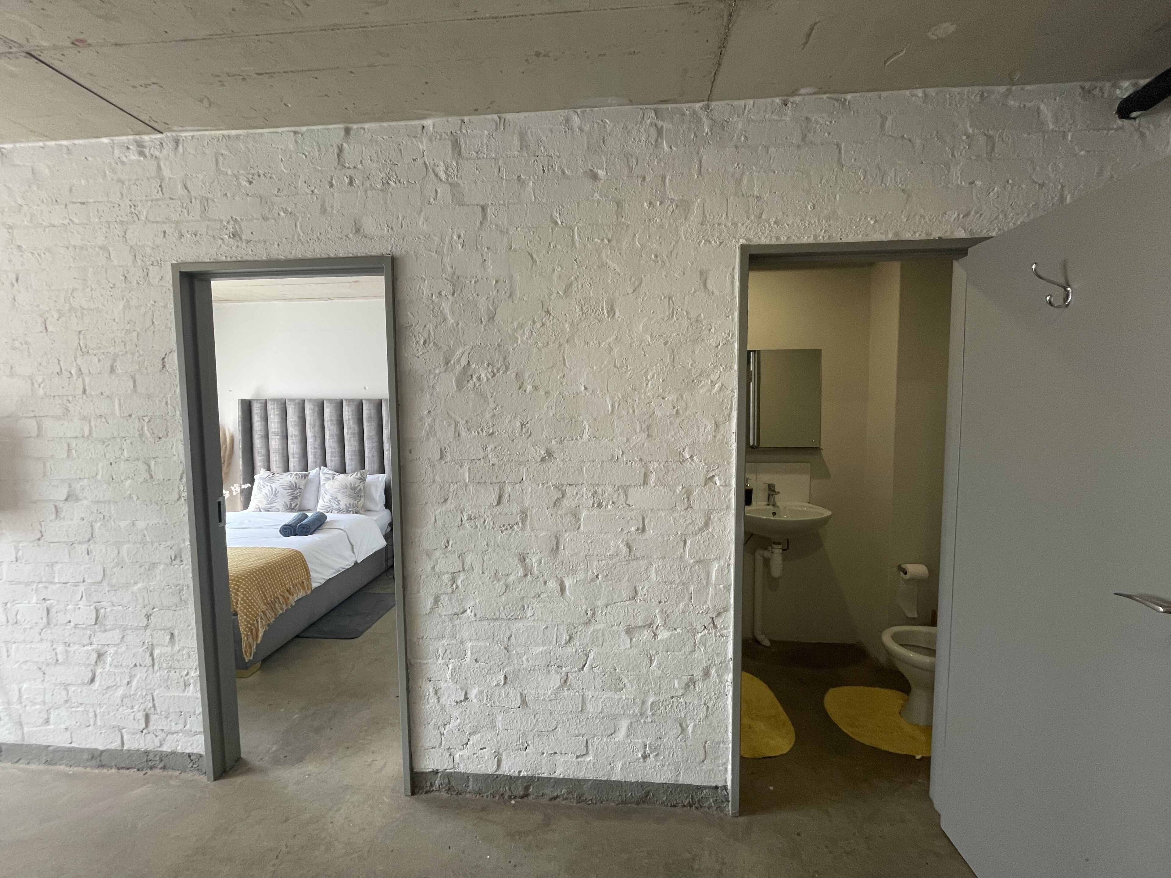 A room with a bed, a bathroom with a sink and toilet, and a mirror.