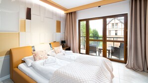 A modern hotel room with a large bed, a nightstand, and a view of the outside balcony. - Apartamenty Sun & Snow Green Park (Szklarska Poreba)