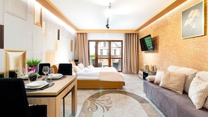 A hotel room with a bed, a sofa, a TV, and a dining area with a table and chairs. - Apartamenty Sun & Snow Green Park (Szklarska Poreba)