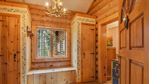 A log cabin interior with a bench by a window, wooden walls, and a chandelier. - Carnelian Lodge Log Cabin, Sleeps 9, Hot Tub (Carnelian Bay)