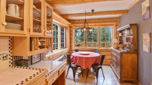 A cozy cabin kitchen with wooden cabinets, a dining table, and a view of the outdoors. - Carnelian Lodge Log Cabin, Sleeps 9, Hot Tub (Carnelian Bay)