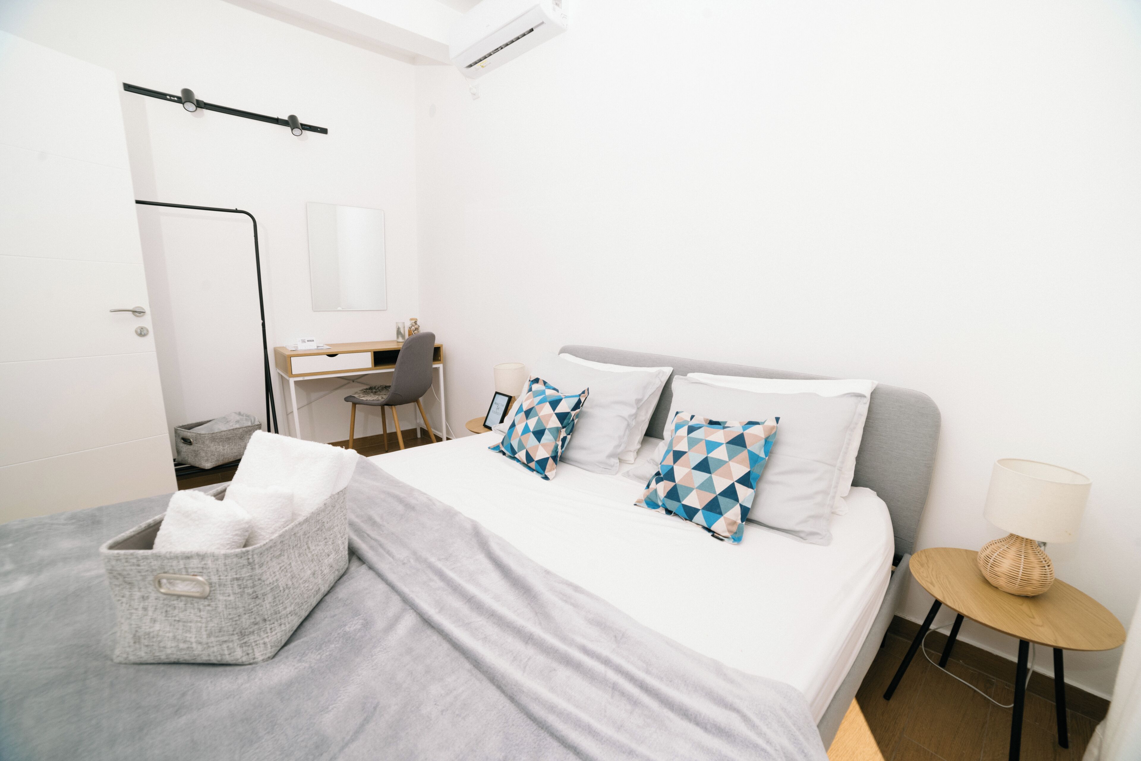 Une chambre d’hôtel moderne équipée d’un lit, d’un bureau, d’une chaise et d’une petite table avec une lampe.