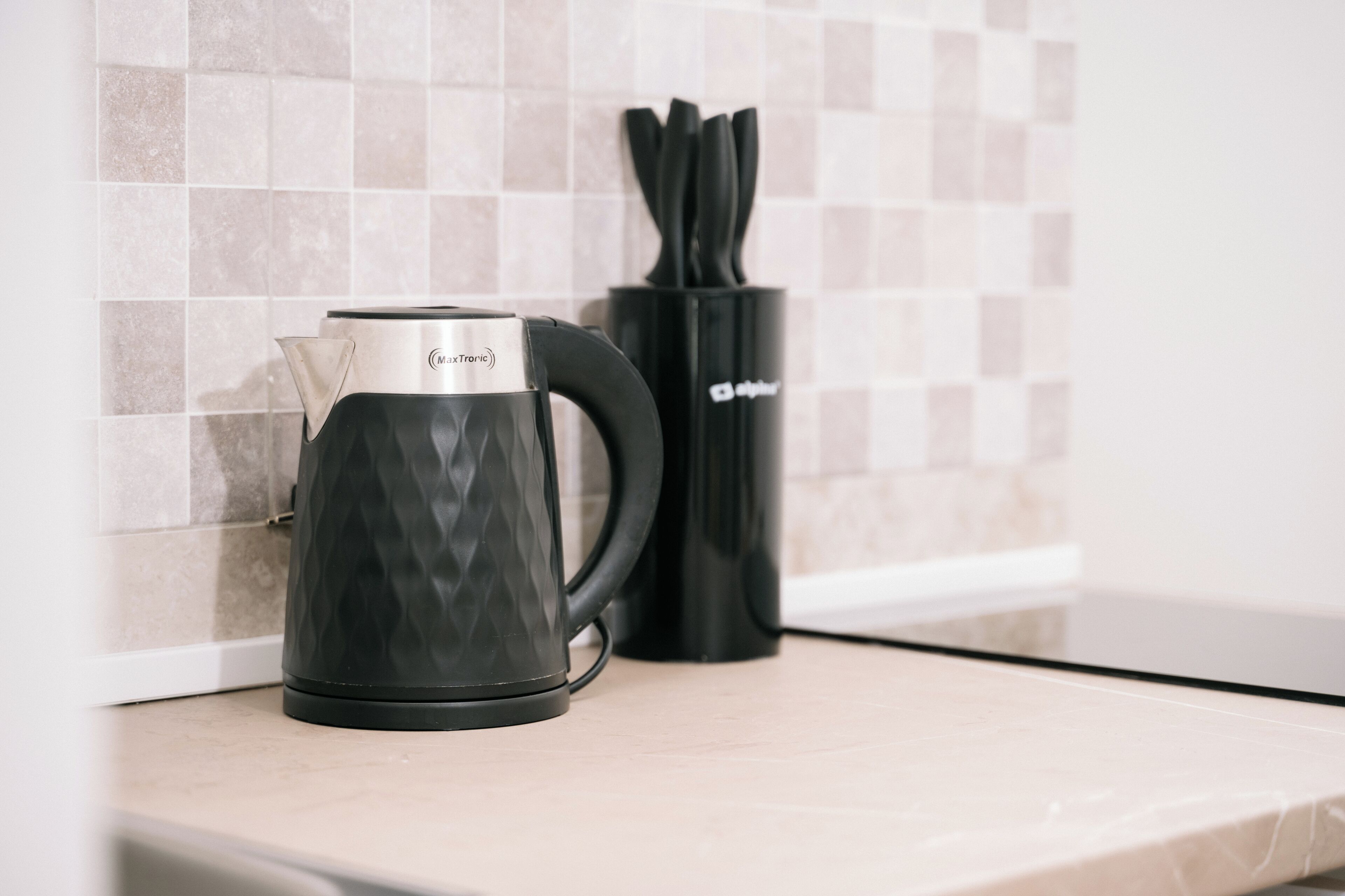A kitchen with a black coffee maker and a knife holder on the counter.