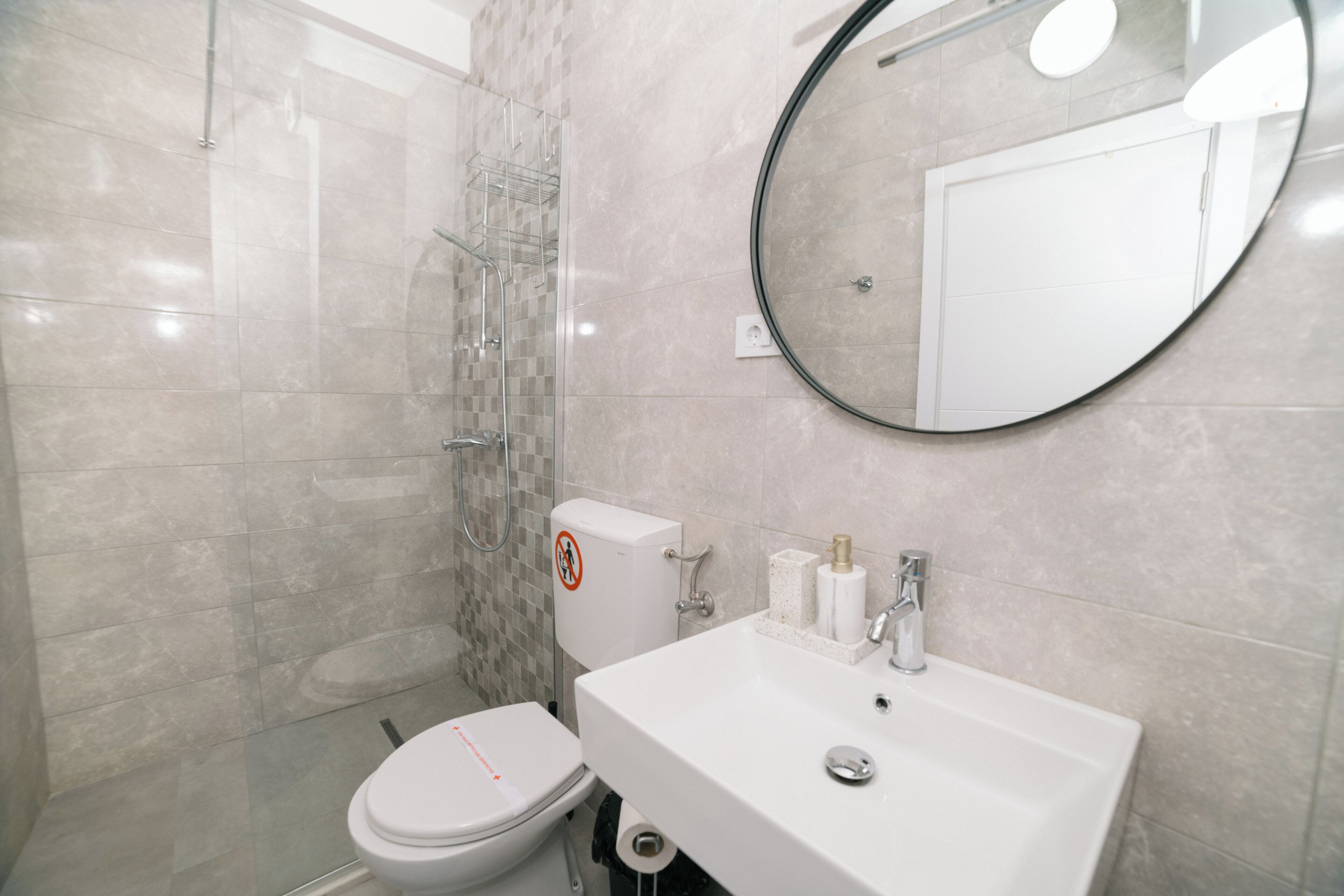 Une salle de bain moderne équipée de toilettes, d’un lavabo et d’une douche.