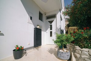 A clean, white-walled outdoor area with a bench, potted plants, and a stone wall. - The Rooftop Apartment with Sea view (Ulcinj)