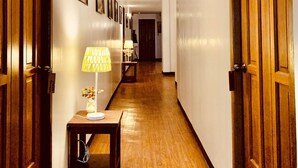 A hallway with wooden doors, a lamp, and framed pictures on the wall. - Tagzzz Hotel powered by Cocotel (Tagaytay)