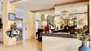 A spacious hotel lobby with a reception desk, a staircase, and a large mirror reflecting the interior. - Tagzzz Hotel powered by Cocotel (Tagaytay)