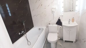 Ein modernes Badezimmer mit Badewanne, Toilette und Waschbecken.