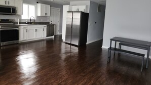 A kitchen with white cabinets, stainless steel appliances, and a wooden floor.